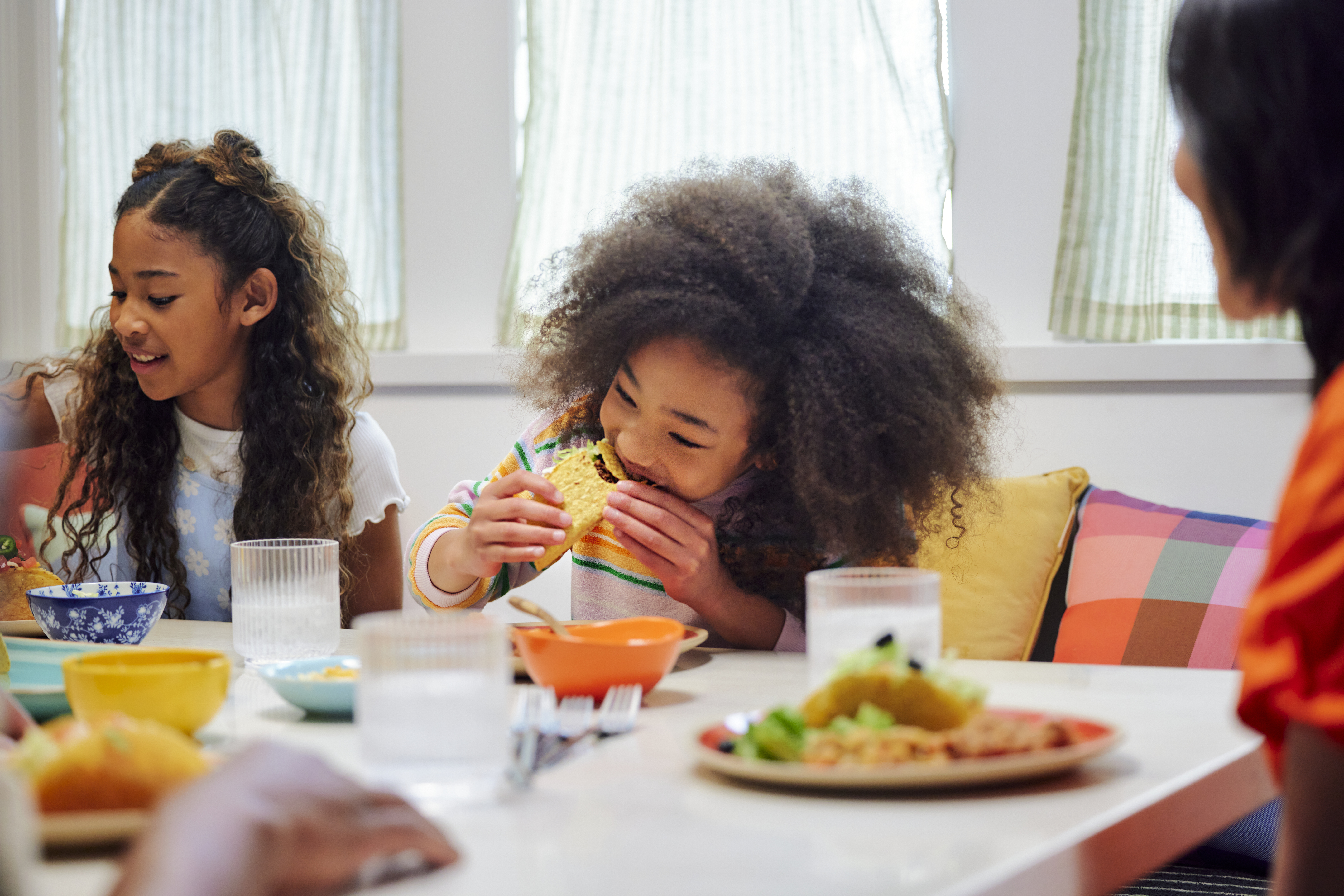 Two girls eating tacos at the dinner table